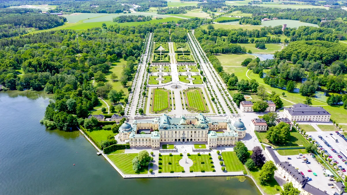 View of the beautifully landscaped gardens at Drottningholm Palace, featuring manicured hedges, flowerbeds, and statues