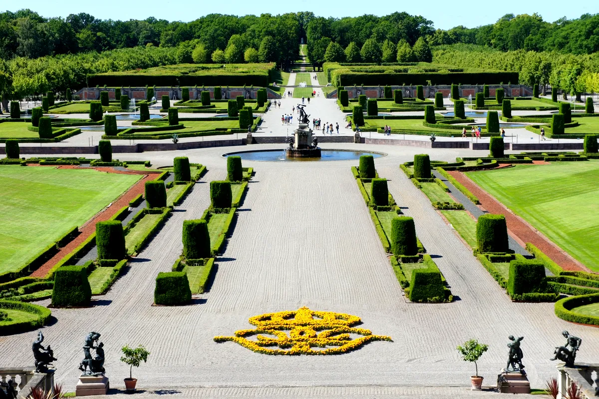 Beautifully manicured gardens of Drottningholm Palace in Sweden, featuring geometric hedges, statues, and fountains.