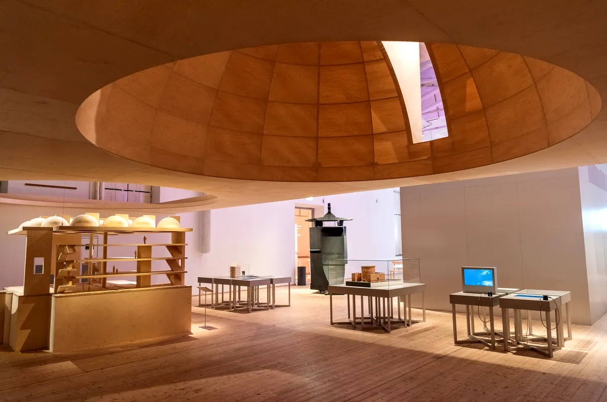 Moderna Museet Stockholm Innenansicht des Moderna Museet in Stockholm mit einer einzigartigen hölzernen Architekturstruktur mit Regalen, Tischen und Kunstausstellungen unter einer großen runden Öffnung in der Decke.