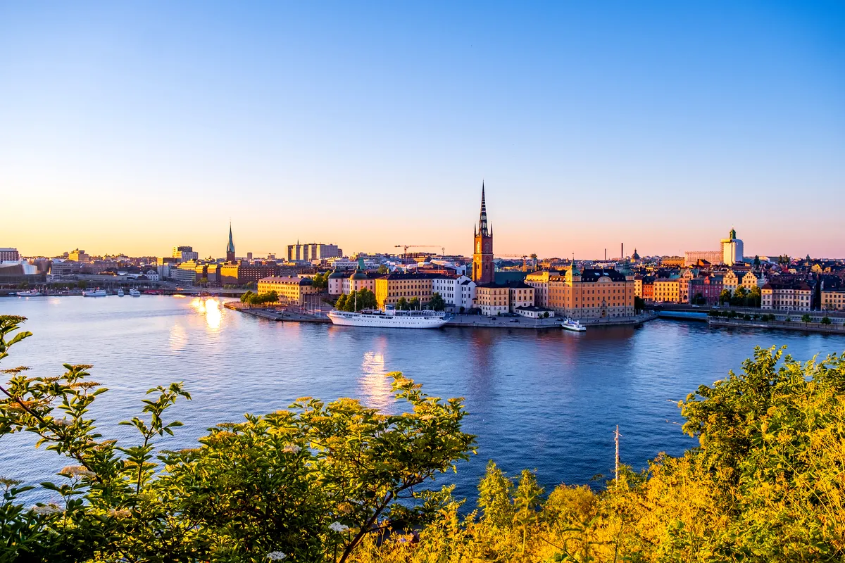 Fantastisk panoramautsikt över Stockholms Gamla Stan vid solnedgången, med historiska byggnader, spiror och vattenreflektioner sett från Monteliusvagen