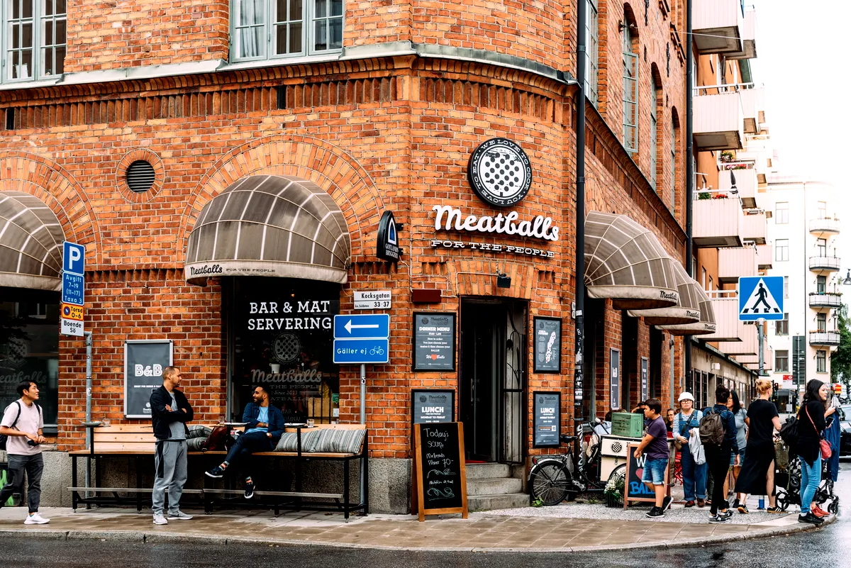 Vibrerande gatubild i Stockholms SoFo-distrikt med populära 'Köttbullar för Folkrestaurang med folk som samlas utanför