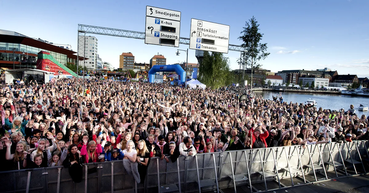 Experience the Excitement of Luleå Hamnfestival: Sweden's Premier Summer Festival En stor, upprymd publik som deltar i Luleå Hamnfestival i Sverige och njuter av utomhusfester och liveframträdanden i en livlig stadsatmosfär.