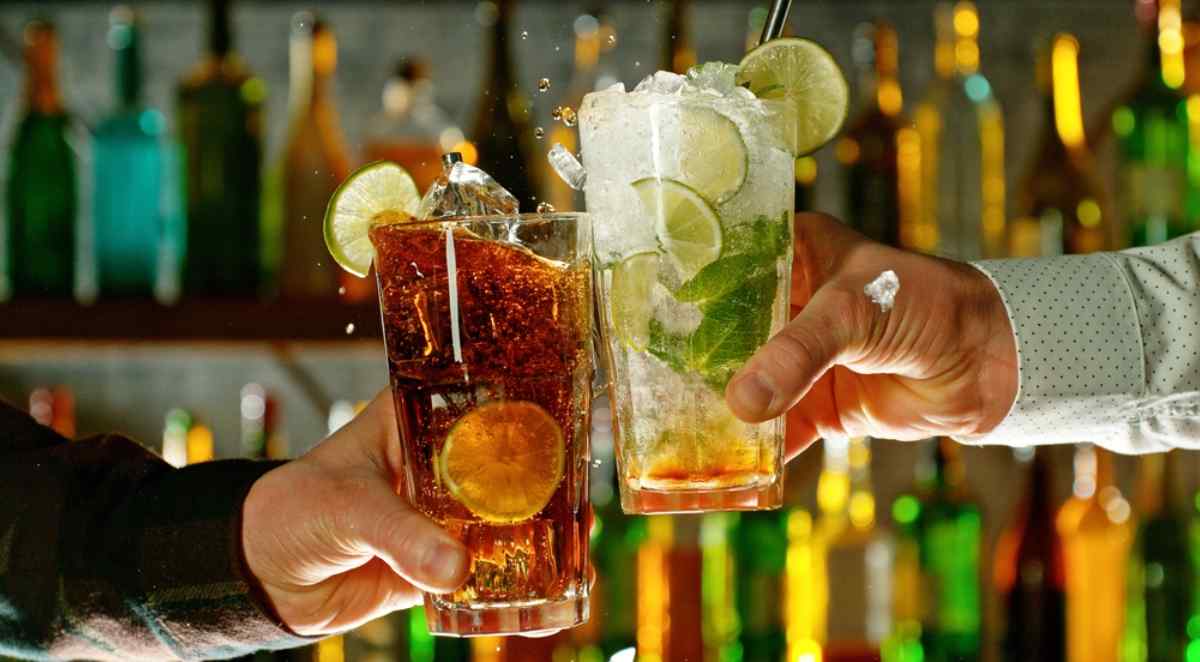 Zwei Hände halten Cocktailgläser und stoßen in einer Bar in Stockholm an